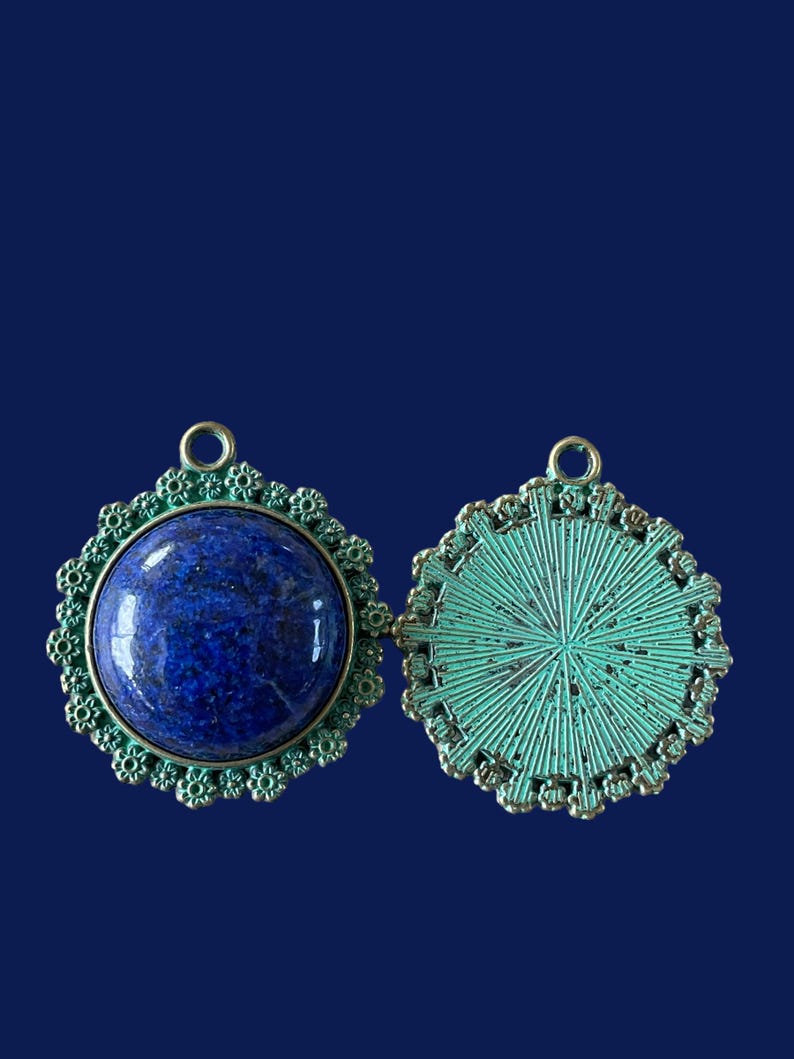 Op de afbeelding: Een paar ronde, sierlijke metalen hangers, een met een blauwe lapis lazuli-steen en de andere met een groen metalen ontwerp.