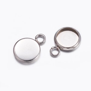 Peut inclure: Deux pendentifs en métal argenté avec une bélière ronde pour une pierre de cabochon. Chaque pendentif a un anneau de saut pour l'attacher à une chaîne ou un cordon.