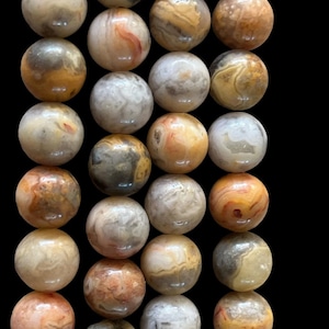 Peut inclure: Un brin de perles rondes en agate de couleur marron, blanc et orange. Les perles ont un motif marbré naturel.