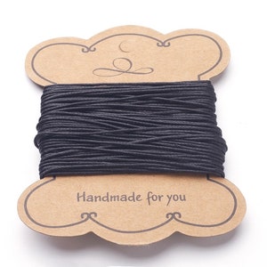 Peut inclure: Une bobine de cordon ciré en coton noir sur une étiquette en carton brun avec le texte "Handmade for you".