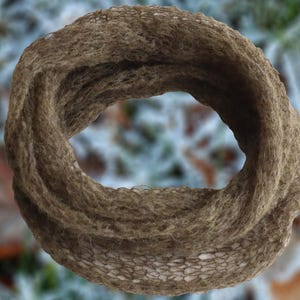 May include: A circular, knitted scarf in shades of brown. The scarf has a textured appearance, with visible stitches and a soft, natural look. The design is a continuous loop, suitable for cold weather.