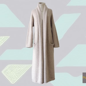 May include: A long, beige, open-front cardigan with a shawl collar and long sleeves, featuring two front pockets. The garment is layered over a matching beige turtleneck sweater. The text "PopsFL" is visible in the bottom right corner.
