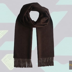 May include: A brown cashmere scarf with fringe on the ends. The scarf is folded in half and laid flat on a light purple background.