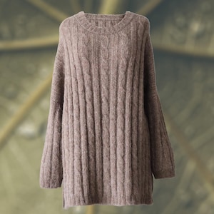 Puede incluir: Un suéter de color topo de manga larga con cuello redondo. El suéter presenta un diseño de punto trenzado y un ajuste relajado. El dobladillo es ligeramente más largo en la espalda. Este suéter acogedor es perfecto para el clima más fresco.