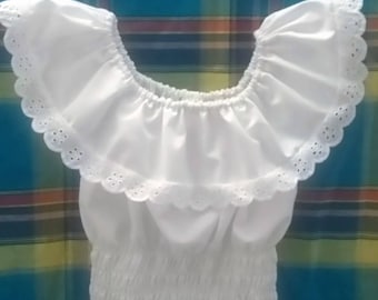 May include: A white off-the-shoulder crop top featuring a wide ruffled neckline with scalloped eyelet lace trim. The garment has a gathered elasticized bodice that creates a textured, shirred appearance throughout the midsection area.