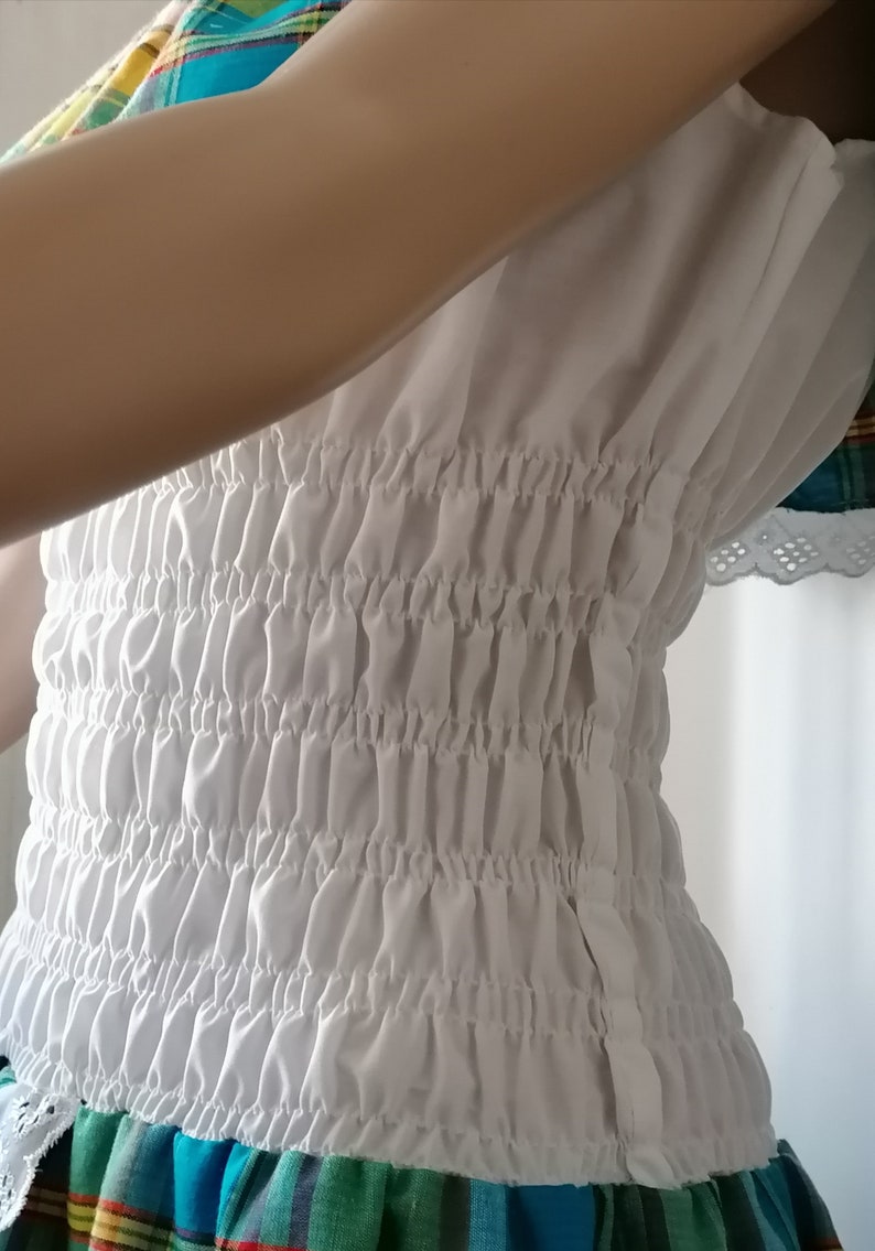May include: White gathered elastic waistband with a zipper closure. The waistband is made of a soft, lightweight fabric.