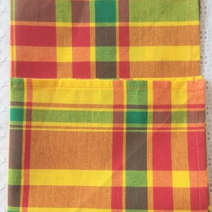 May include: Two yellow, red, green, and brown checkered fabric napkins.