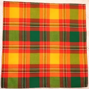 May include: A red, yellow, green, and brown plaid fabric placemat. The fabric has a woven texture.
