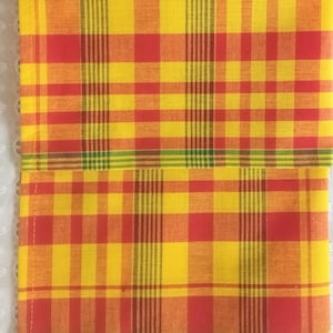 May include: Two red, yellow, and green checkered kitchen towels. The towels are folded in half and have a woven texture.