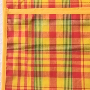 May include: A yellow, red, and green plaid fabric with a yellow border. The fabric is woven with a checkered pattern.
