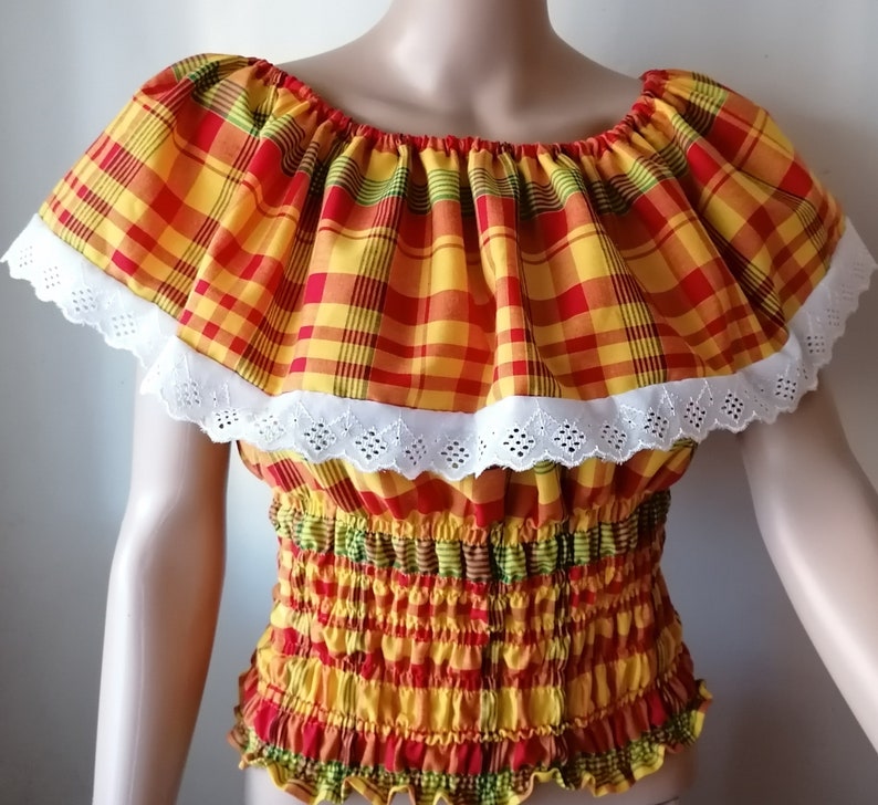 May include: A red, yellow, and green plaid off-the-shoulder top with white lace trim and a gathered elastic waistband.