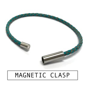 Puede incluir: Un brazalete de cuero azul turquesa con un tejido de cuero marr&oacute;n y un cierre magn&eacute;tico. El cierre es de acero inoxidable.