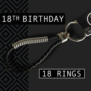 May include: Black leather keychain with silver accents. The keychain has a braided design and a metal ring. Text on the image reads "18th Birthday" and "18 Rings".