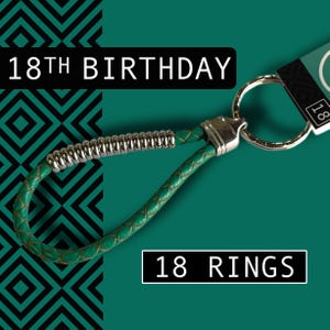 May include: A green leather keychain with a silver metal clasp and a coiled silver accent. The keychain is attached to a silver ring. The text "18TH BIRTHDAY" and "18 RINGS" are displayed on the image.