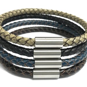 May include: A multi-layered leather bracelet with a braided design in black, brown, beige, and blue. The bracelet has a silver magnetic clasp.