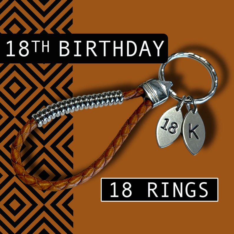May include: A brown leather keychain with a silver ring and two leaf-shaped charms. The charms are engraved with "18" and "K". The keychain has the text "18TH BIRTHDAY" and "18 RINGS" in the image.