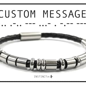 May include: A black leather bracelet with silver metal beads and a magnetic clasp. The bracelet has the text "CUSTOM MESSAGE" and a series of dots and dashes, which is Morse code.