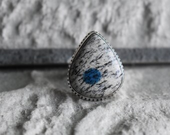 May include: A silver ring with a teardrop-shaped blue and white gemstone. The gemstone has a swirling pattern and a blue center.