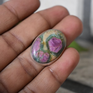 Peut inclure: Une bague en argent avec une pierre ovale rose, verte et blanche. La pierre a un motif unique de rose et de vert.