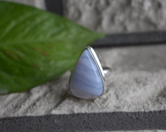 May include: A silver ring with a blue agate gemstone in a triangle shape.