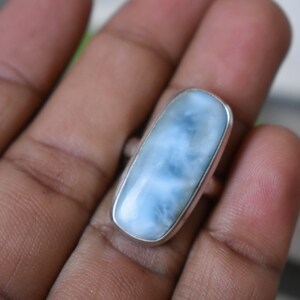 May include: A silver ring with a light blue, rectangular, cloudy gemstone.
