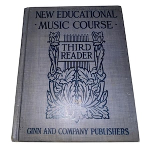 May include: A vintage book titled "New Educational Music Course - Third Reader" with a blue cover and dark blue lettering. The cover features an ornate design with a harp and floral elements. The publisher's name, Ginn and Company, is printed at the bottom.