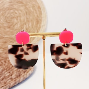 Puede incluir: Un par de pendientes con un diseño rosa y carey. Los pendientes están hechos de acrílico y tienen un cierre de poste.