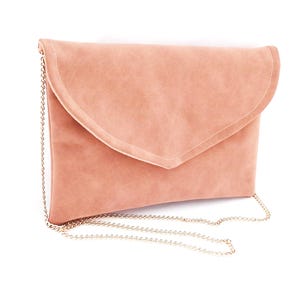 Puede incluir: Un bolso de mano color rubor con cierre de solapa y una delicada cadena dorada. El bolso tiene una textura suave, similar al ante, y un diseño sencillo y elegante. Este versátil accesorio es adecuado para diversas ocasiones.