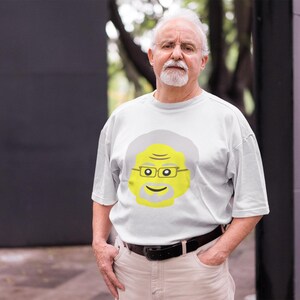 May include: A white t-shirt with a yellow cartoon face of a man with gray hair and glasses. The man is smiling.