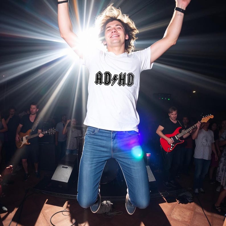 Happy young man jumping in spotlight at live show, wearing white shirt with bold AD HD design, ideal ADHD rock band SVG cut file for Cricut or Silhouette.