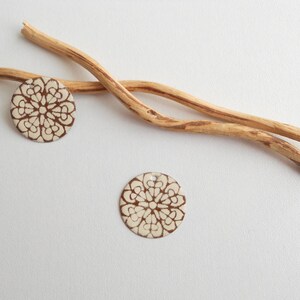 Może przedstawiać: Dwa białe, okrągłe płytki ceramiczne z brązowym wzorem kwiatowym. Płytki leżą na białym tle z dwoma drewnianymi patykami.