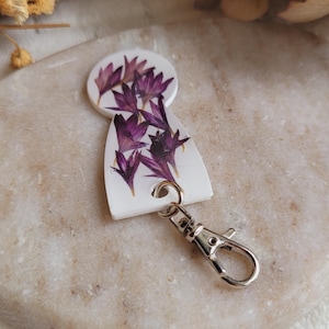 樹脂と乾燥した紫色のヤグルマギクの花で作られたショッピングカートのトークン。ショッピングアクセサリー。ショッピングカートトークンキーチェーン。
