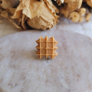 Peut inclure: Une bague en résine de couleur brune en forme de gaufre avec une surface texturée.