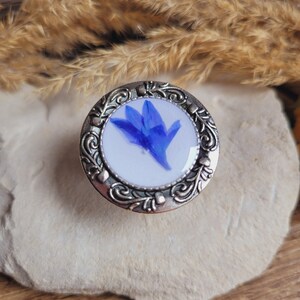 Adjustable baroque style ring in stainless steel - white resin tray with dried cornflower flower.
