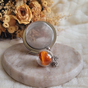 Glass sphere tea ball and dried marigold flower petals. Flowery tea ball. Flowery tea infuser.