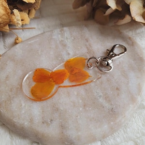 樹脂と乾燥したインドのピンクの花で作られたショッピングカートのトークン。ショッピングアクセサリー。ショッピングカートトークンキーチェーン。