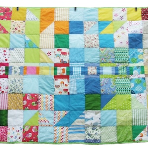 Peut inclure: Une courtepointe colorée en patchwork réalisée à partir de différents morceaux de tissu. La courtepointe est composée de carrés et de triangles de différentes couleurs, notamment le vert, le bleu, le jaune, le rouge et le blanc. La courtepointe est bordée d'une bordure verte.