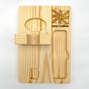 Puede incluir: Un organizador rectangular de madera clara con una bandera Union Jack grabada y el texto Carve Creations. La tabla incluye un estante horizontal, una hendidura circular, una ranura rectangular y un peque&ntilde;o recorte cuadrado para almacenamiento.
