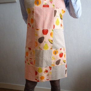 Peut inclure: Tablier patchwork orné d'illustrations de fruits, notamment des pommes, des poires et des oranges. Le tablier présente un motif vichy rose et blanc et un fond rose clair. Idéal pour la cuisine.