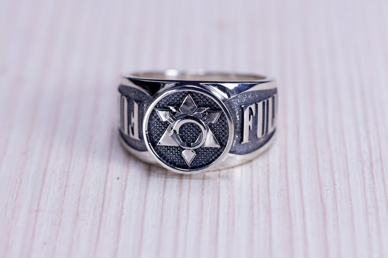 May include: A silver ring with a central star design and the word "FULL" on the band. The ring has a detailed, textured surface and a polished finish, suitable for everyday wear.