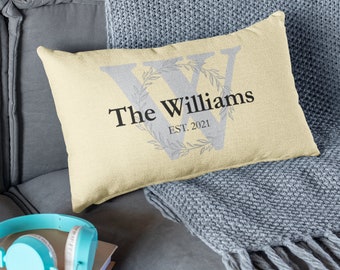 May include: A yellow throw pillow with the text "The Williams EST. 2021" and a gray letter W with a wreath of leaves around it.