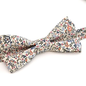 Peut inclure: Un nœud papillon blanc avec un motif floral dans des tons de bleu, rose et orange.