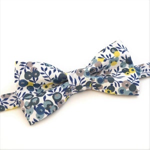 Peut inclure: Un nœud papillon blanc avec un motif floral dans les tons bleus, jaunes et gris.