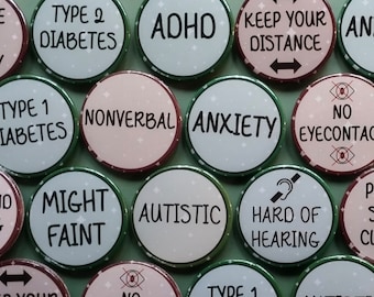Puede incluir: Una colección de botones redondos con varios textos y símbolos. Los botones son verdes, blancos y rosas con texto negro. Algunos de los textos incluyen "Diabetes tipo 1", "Diabetes tipo 2", "TDAH", "Mantenga la distancia", "Ansiedad", "No verbal", "Puede desmayarse", "Autista", "Dificultad auditiva", "Sin contacto visual".