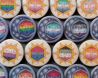 May include: A collection of 12 round, colorful buttons with a rainbow-colored 20-sided die design. Each button features a different design with a sun or moon graphic.