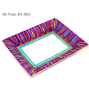 May include: Rectangular decorative tray with a white interior and a vibrant, hand-painted design. The border features a repeating pattern of purple, orange, and yellow leaf-like shapes, outlined in black. The tray has a turquoise border around the white interior. The text "De Vous Art Moi" is in the upper left corner.