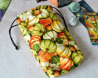 May include: A drawstring bag made of fabric with a pumpkin print. The bag is green, white and orange with a black drawstring.