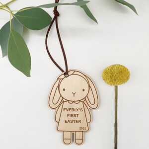 Puede incluir: Adorno de madera con forma de conejita con el texto "Everly's First Easter 2022" en &eacute;l.