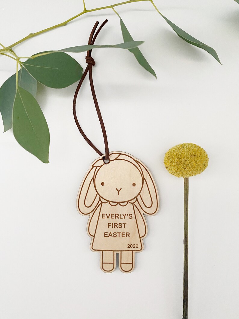 Puede incluir: Adorno de madera con forma de conejita con el texto "Everly's First Easter 2022" en &eacute;l.