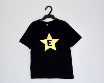 Camiseta negra con estrella dorada y letra del nombre, camiseta negra de superhéroe con estrella, camiseta de superhéroe con estrella dorada